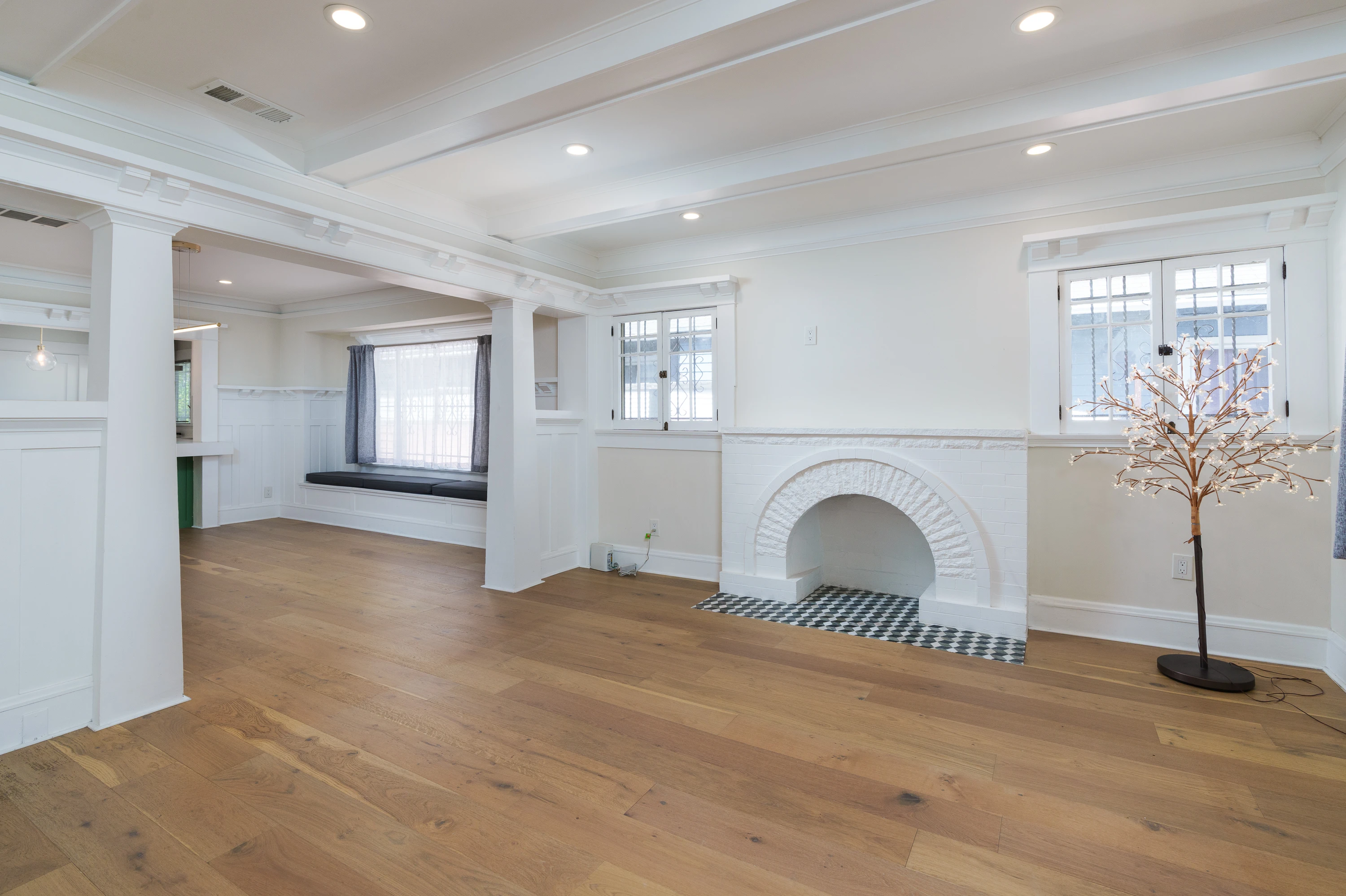 Vacant living room with an arched brick fireplace and white oak floors