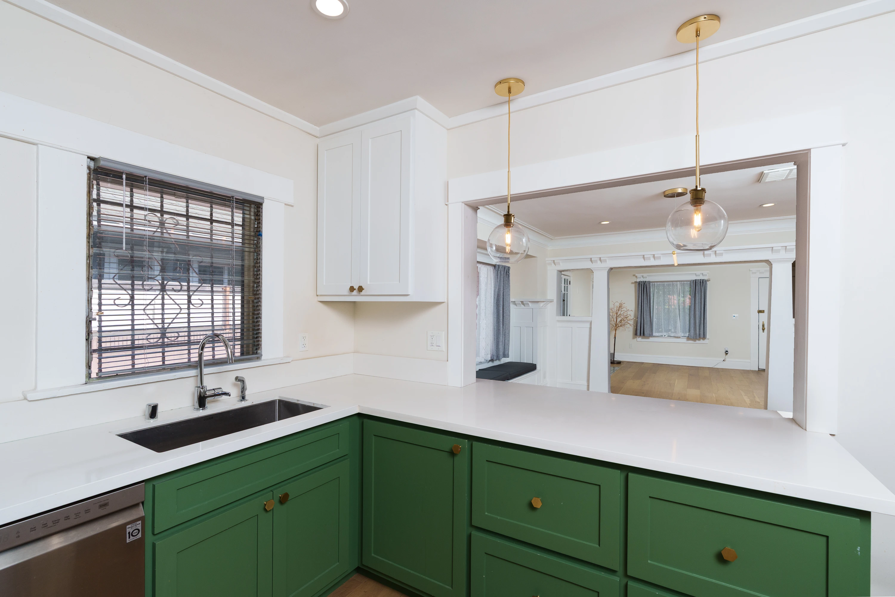 Kitchen with green cabinets, white quartz counters and brass pendants